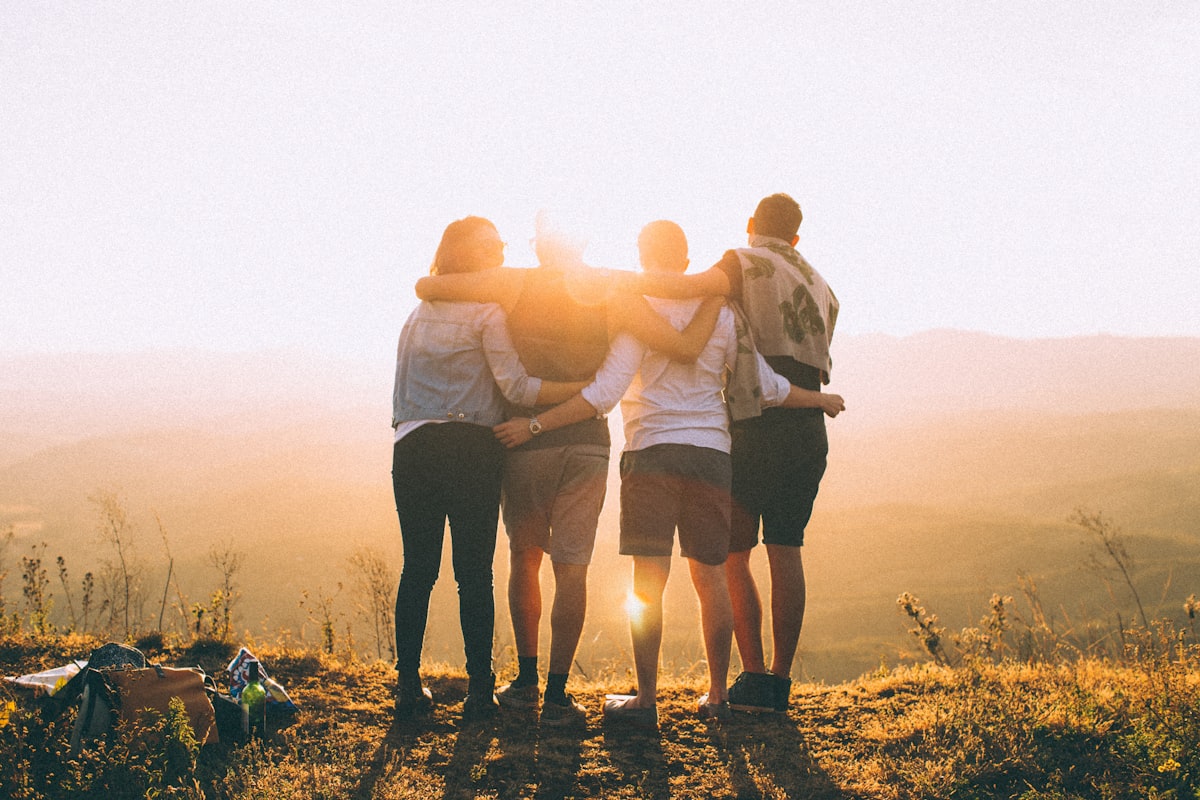 Quatre amis enlacés devant un coucher de soleil